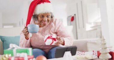 Mutlu son sınıf Afro-Amerikan kadını Noel 'de akıllı telefon kullanarak video araması yapıyor. Emeklilik, evde vakit geçirme ve Noel konsepti.