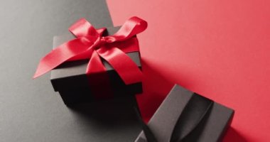 Siyah ve siyah kurdeleli iki siyah hediye kutusuna yakın. Siyah ve kırmızı kurdeleler ve fotokopi alanı. Lüks ikram, mevcut, alışveriş, kara Cuma indirimi ve dijital olarak üretilen video konsepti.