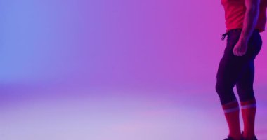 Kafkasklı beyaz amerikalı futbolcunun neon mor arka planı üzerinde fotokopi alanı olan videosu. Amerikan futbolu, spor ve yarışma konsepti.