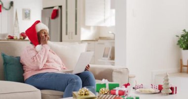 Mutlu son sınıf Afro-Amerikan kadını Noel 'de dizüstü bilgisayar kullanarak video görüşmesi yapıyor. Emeklilik, evde vakit geçirme ve Noel konsepti.