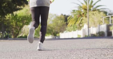 Sunny Caddesi 'nde koşan yaşlı, çift ırklı, spor elbiseli bir adamın dikiz görüntüsü. Emeklilik, hobiler, sağlık, kapsayıcılık ve aktif kıdemli yaşam tarzı konsepti.