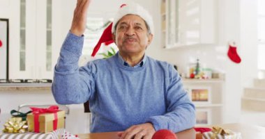 Noel Baba şapkalı son sınıf melez adamın Noel 'de kameraya el salladığı bir video. Noel, gelenek, küresel iletişim, kapsayıcılık ve kıdemli yaşam tarzı konsepti.