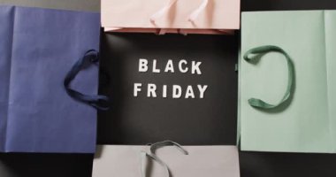 Siyah renkli hediye paketleriyle siyah üzerine beyaz yazılı siyah cuma metni. Kara Cuma, alışveriş, satış ve perakende konsepti dijital olarak oluşturulmuş video.