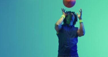 Yeşil arka planda topu olan çift ırklı erkek basketbolcunun videosu. Spor ve rekabet konsepti.