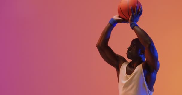 Vídeo Jugador Baloncesto Afroamericano Lanzando Pelota Sobre Fondo Rosa Naranja — Vídeo de stock