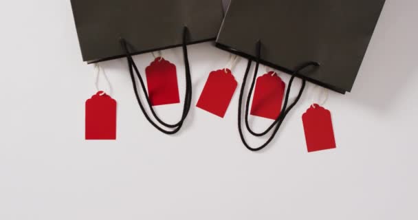 Beyaz Arka Planda Beş Kırmızı Etiketli Iki Siyah Hediye Çantası — Stok video
