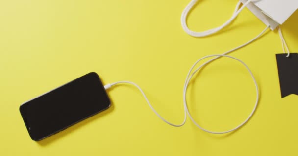 Akıllı Telefon Sarı Arka Planda Siyah Etiketli Beyaz Hediye Çantasının — Stok video