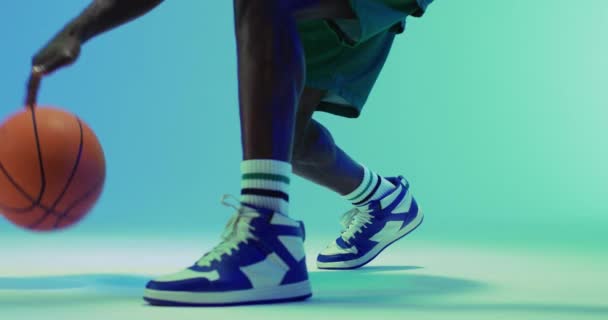 アフリカ系アメリカ人男性バスケットボール選手が青い背景でボールを跳ねる映像 スポーツ 競技の概念 — ストック動画