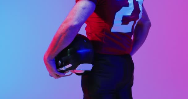 在霓虹灯紫色背景上戴头盔的高加索美式足球运动员中段视频 美国足球 体育和竞争概念 — 图库视频影像