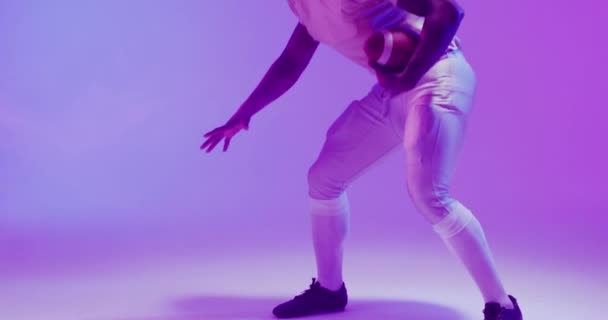 Video Eines Afrikanisch Amerikanischen Fußballspielers Mit Ball Vor Violettem Hintergrund — Stockvideo