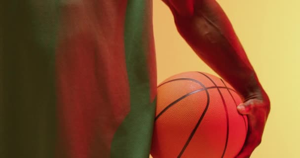 オレンジ色の背景にボールを保持アフリカ系アメリカ人男性バスケットボール選手の中央部のビデオ スポーツ 競技の概念 — ストック動画