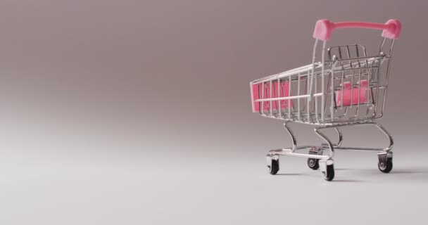 シームレスグレーの背景に空のピンクのショッピングトロリー 贅沢な治療 ショッピング 小売コンセプトデジタル生成ビデオ — ストック動画