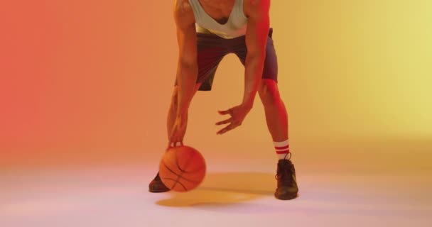 オレンジ色から黄色の背景にボールをバウンス出生男性バスケットボール選手のビデオ スポーツ 競技の概念 — ストック動画