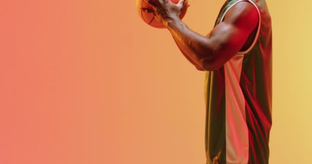 オレンジ色の背景にボールを保持アフリカ系アメリカ人男性バスケットボール選手のビデオ スポーツ 競技の概念 — ストック動画