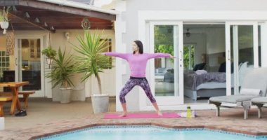 Çift ırklı kadın bahçede yoga ve esneme pratiği yapıyor.
