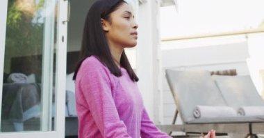 Çift ırklı kadın bahçede yoga ve meditasyon yapıyor.