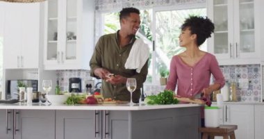 Afro-Amerikan çifti mutfakta yemek pişirip şarap içiyor. Evde birlikte vakit geçirmek kavramı..