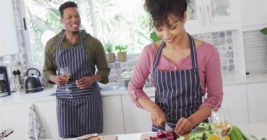 Afro-Amerikan çifti mutfakta yemek pişirip şarap içiyor. Evde birlikte vakit geçirmek kavramı..