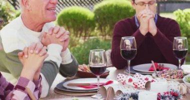 Bahçede yemekten önce dua eden Kafkasyalı mutlu bir aile. Ev kavramında aileyle kaliteli zaman geçirmek.