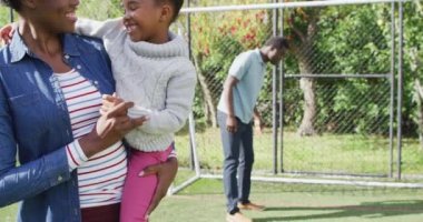 Parkta futbol oynayan mutlu Afro-Amerikan ailesinin portresi. Aileyle açık hava konsepti ile kaliteli zaman geçirmek.