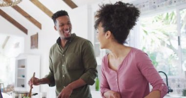 Afro-Amerikan çiftimiz mutfakta yemek pişirip sohbet ediyor. Evde birlikte vakit geçirmek kavramı..