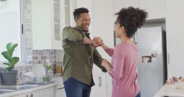 Mutlu Afro-Amerikan çiftler mutfakta dans edip el ele tutuşuyorlar. Evde birlikte vakit geçirmek kavramı..