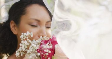 Çiçekli, gelinlik giyen mutlu Afro-Amerikalı kadın. Düğün günü, evlilik ve kutlama konsepti.