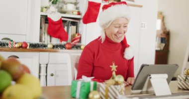 Noel Baba şapkası takan, video araması için tablet kullanan mutlu Kafkasyalı kadın. Noel 'de evde yalnız vakit geçirmek..