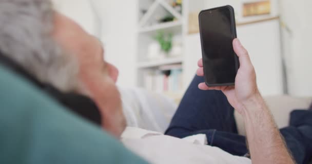 Oturma Odasındaki Kanepede Uzanmış Akıllı Telefon Kullanan Mutlu Beyaz Adam — Stok video