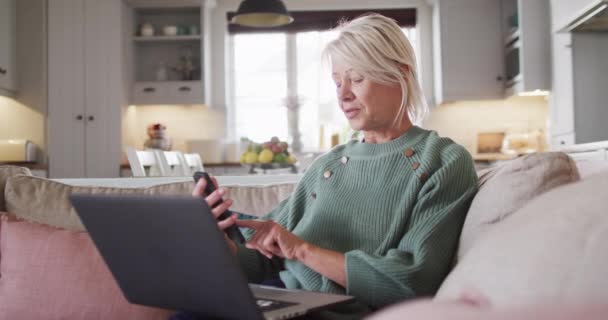 Счастливая Старшая Белая Женщина Сидит Диване Гостиной Используя Ноутбук Смартфон — стоковое видео
