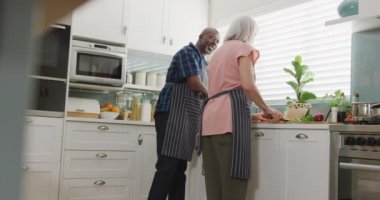 Önlük giyip mutfakta yemek pişiren mutlu kıdemli çift. Evde ve emeklilik konseptinde kaliteli zaman geçirmek.