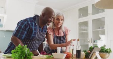 Önlük giyip mutfakta yemek pişiren mutlu kıdemli çift. Evde ve emeklilik konseptinde kaliteli zaman geçirmek.