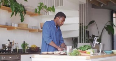 Afro-Amerikalı adam, tablet kullanarak mutfakta yemek pişiriyor. Evde yalnız zaman geçirmek..