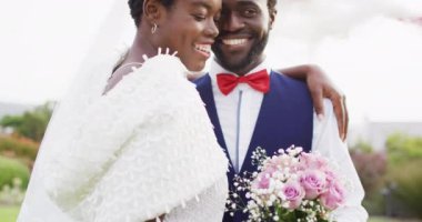 Mutlu Afro-Amerikan çifti düğün sırasında kucaklaşıp gülümsüyor. Düğün günü, arkadaşlık, kapsayıcılık ve yaşam tarzı konsepti.