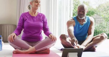 Yoga yapan ve tablet kullanan mutlu kıdemli çift. Evde ve emeklilik konseptinde kaliteli zaman geçirmek.