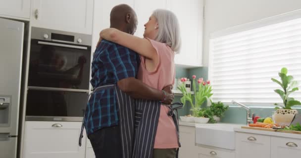 Feliz Casal Diversificado Sênior Vestindo Aventais Abraçando Cozinha Gastar Tempo — Vídeo de Stock