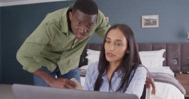 Evdeki yatak odasında dizüstü bilgisayar ve tablet kullanan farklı çiftlerin videosu. İletişim, ev hayatı ve kapsayıcılık kavramı.