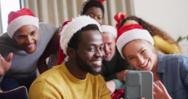 Mutlu bir grup arkadaş yılbaşı partisinde akıllı telefondan telefon kullanıyor. Noel 'de evde birlikte vakit geçirmek..