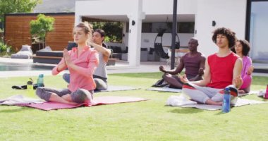 Mutlu bir grup arkadaş bahçede yoga yapıyor, meditasyon yapıyor. Birlikte evde güzel vakit geçirmek..