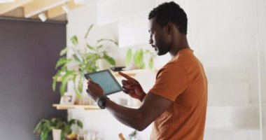 Mutlu Afro-Amerikan adam hava tahmini için tablet kullanıyor. Evde yalnız zaman geçirmek..