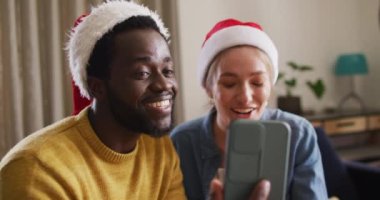 Mutlu bir grup arkadaş yılbaşı partisinde akıllı telefondan telefon kullanıyor. Noel 'de evde birlikte vakit geçirmek..