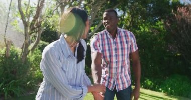 Mutlu çiftin el ele tutuşup güneşli bahçede gülümsediği bir video. Mutluluk, sağlık, aşk, ev hayatı ve kapsayıcılık kavramı.