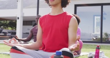 Mutlu bir grup arkadaş bahçede yoga yapıyor, meditasyon yapıyor. Birlikte evde güzel vakit geçirmek..