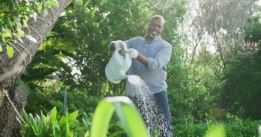 Mutlu kıdemli Afro-Amerikan adam bahçede çalışıyor. Evde ve emeklilik konseptinde kaliteli zaman geçirmek.
