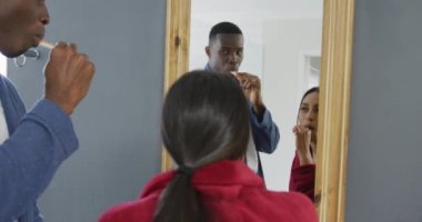 Evdeki banyoda aynada dişlerini fırçalayan mutlu çiftin videosu. Mutluluk, aşk, ev hayatı ve kapsayıcılık kavramı..