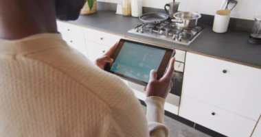 Afrika kökenli Amerikalı bir adamın hava tahmini için tablet kullanması. Evde yalnız zaman geçirmek..