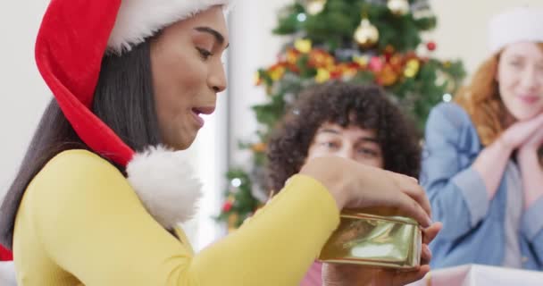 クリスマスプレゼントを開く多様な友人の幸せなグループ クリスマスに家で一緒に質の高い時間を過ごす — ストック動画