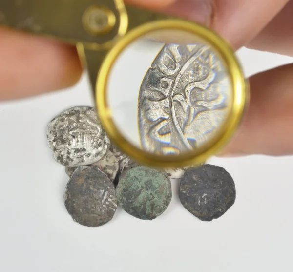 Forstørrelsesglas i hånden og gamle sølvmønter - Stock-foto