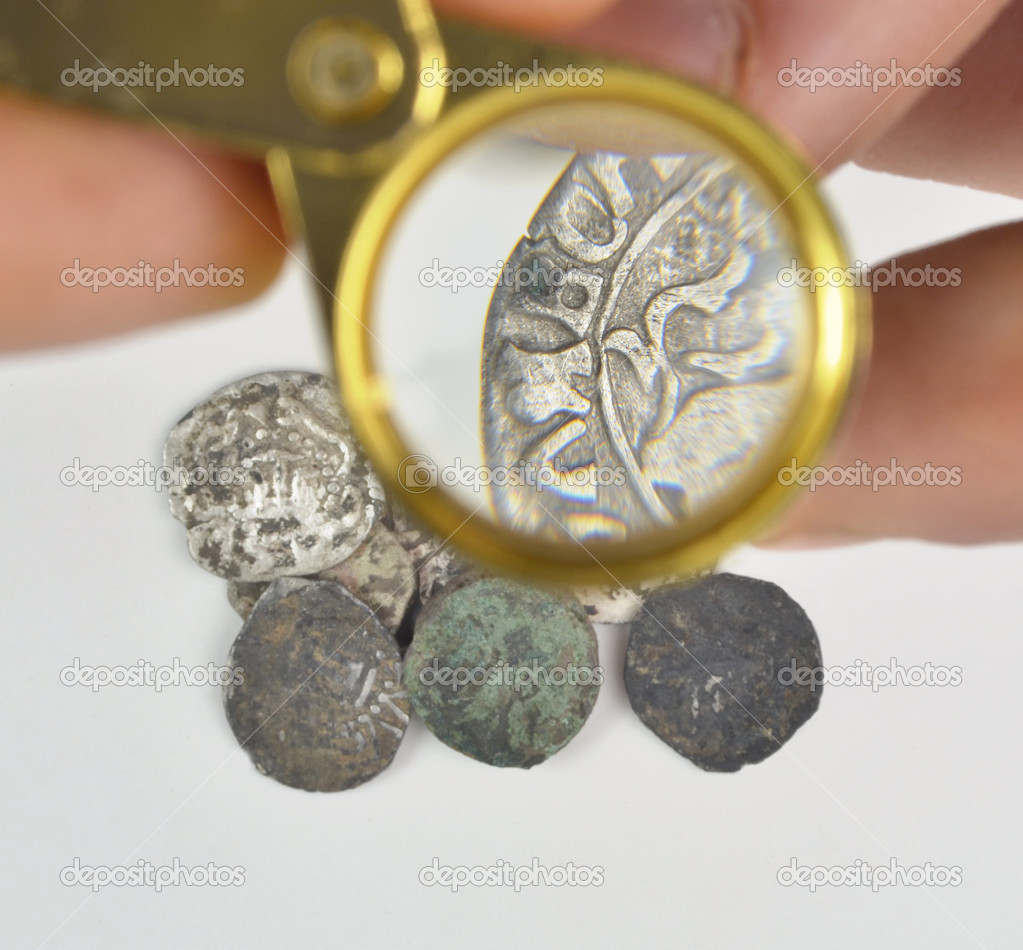 Magnifying glass in hand and old silver coins Stock Photo by