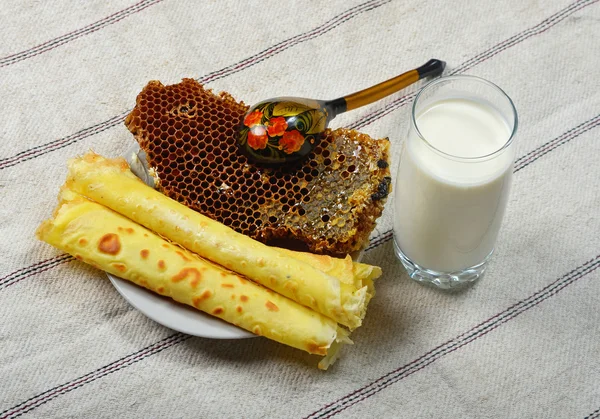 Miel en el peine, leche y panqueques en la mesa Fotos De Stock